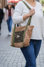 Cabas en velours camel doré et feuille de ginkgo kaki et noir porté à l’épaule d'une femme marchant dans une rue elle porte un jean et un pull fon blanc 