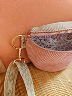 Zoom sur un sac banane entre ouvert en velours cotelé beige et rose. Interieur en coton motif indien pastel. Mercerie doré et bandoulière beige et écru