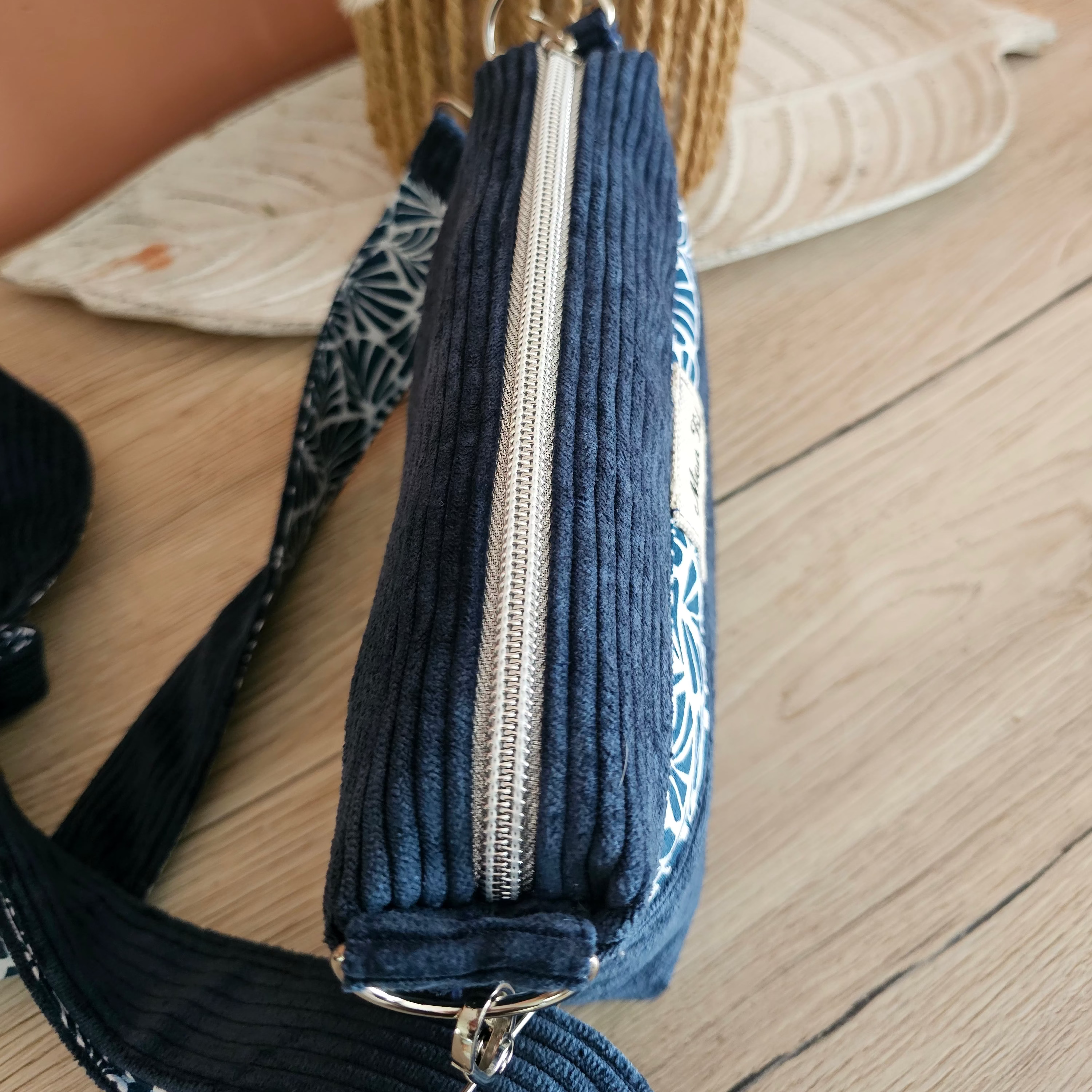 Zoom sur la fermeture zippée au couleur argenté pailleté qui s'harmonise parfaitement avec la couleur de l'anneau mousqueton et regulateur argenté et le velours denim