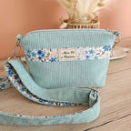 Vue extérieur du crossbody avec un velours vert d'eau et une bande de tissus fleurie en rappelle de la doublure cousus sur le devant avec l'étiquette Mon Fil à Passion sangle bandoulière assortie aux coloris et matières du sac