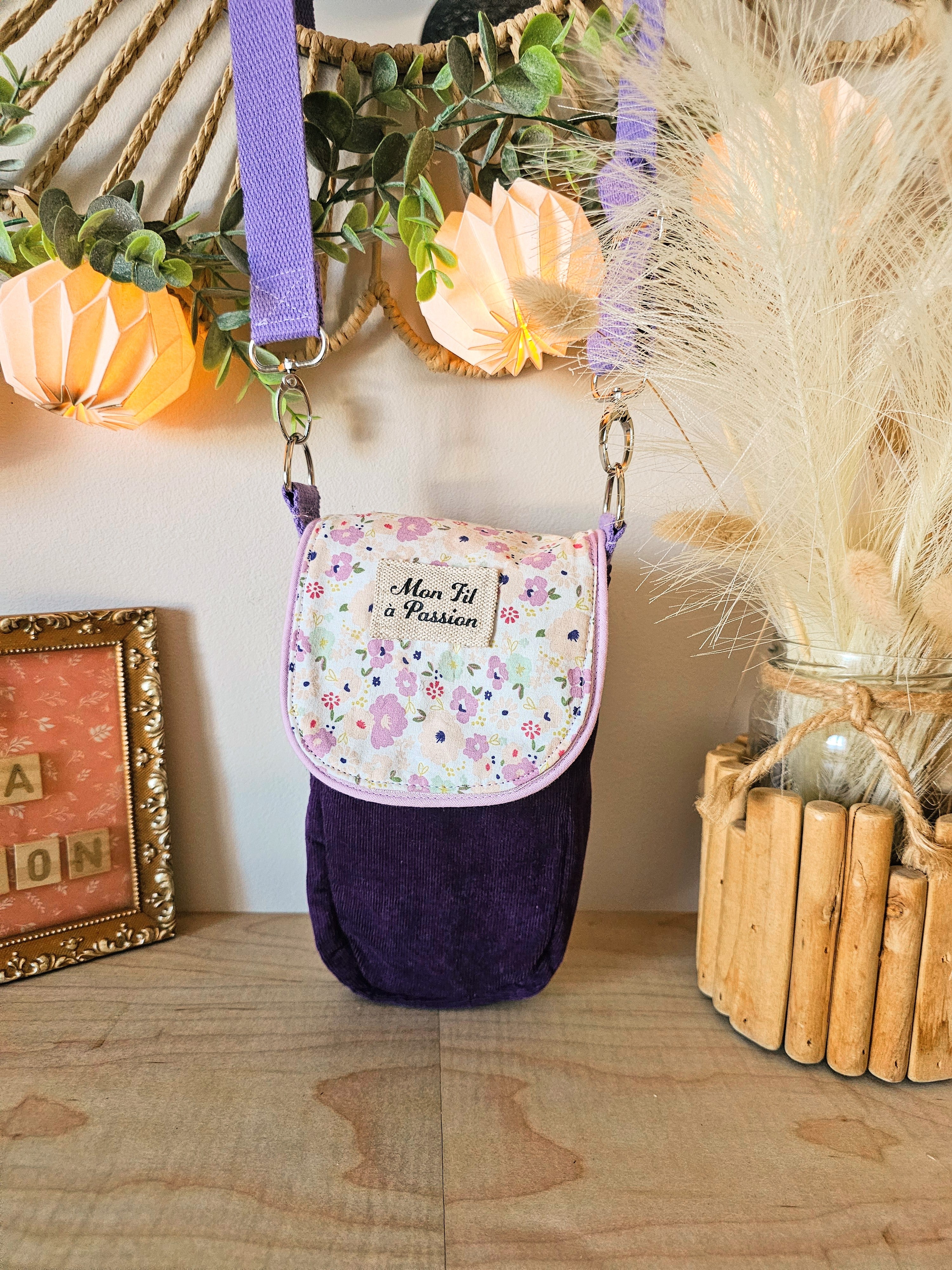 Pochette bandoulière artisanale en velours violet et coton fleuris dans les tons parmes pour transporter un appareil TENS ou un téléphone, avec passage de fils sécurisés.