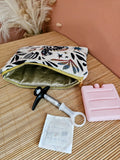 Pochette posée sur une table. Contient un médicament type piqûre injection qui nécessite d'être conserver au frais lors des transports ou voyage. Un bloc de glace et une compresse désinfectante. Trousse isotherme médicale au couleur beige et bleu et motif mystique. Coton enduit doré.