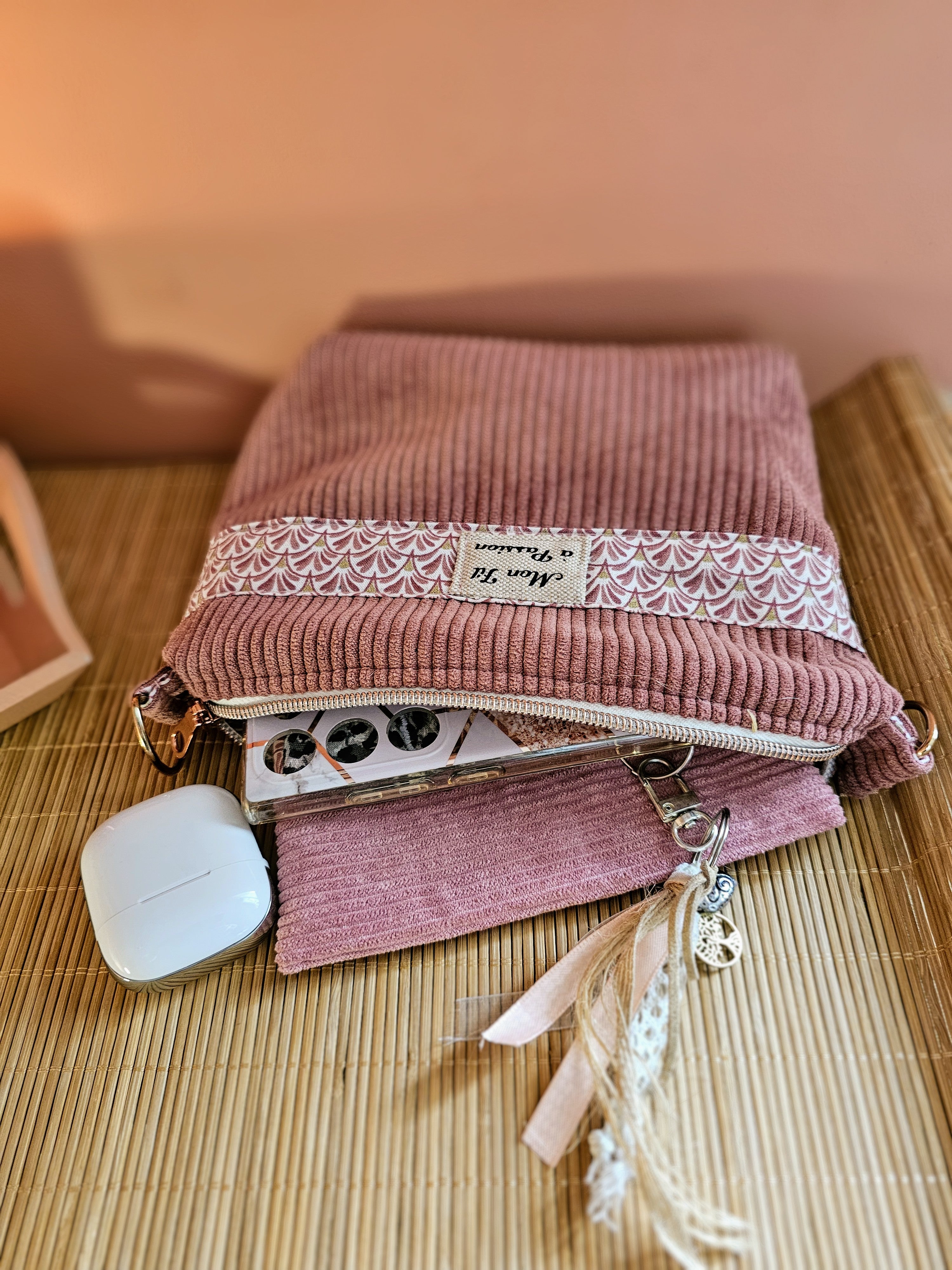 Pochette 2-en-1 convertible en sac bandoulière en velours rose et tissus coton petits éventails dans les tons rose. La pochette est posée sur une console d'entrée et contient les essentiels à transporter. Fait main personnalisable 