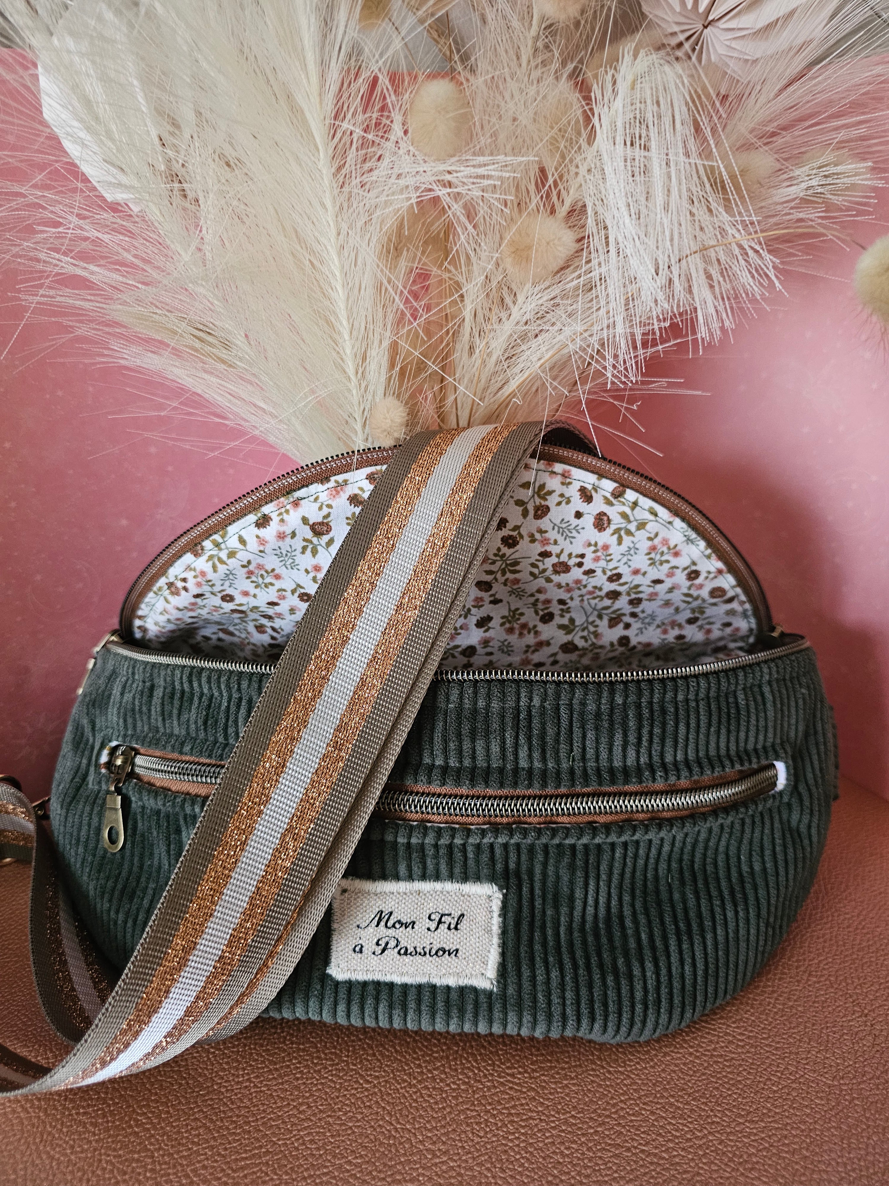 sac banane fait main en velours, ouverture avec  fermeture éclaire et 2 curseurs. l'intérieur montre le tissu en coton liberty dans les tons vert et marron. une bandoulière kaki et bronze brillant harmonise le tout. une poche zipée est présente sur le devant du sac banane ainsi que l'étiquette de la créatrice Mon fil à passion